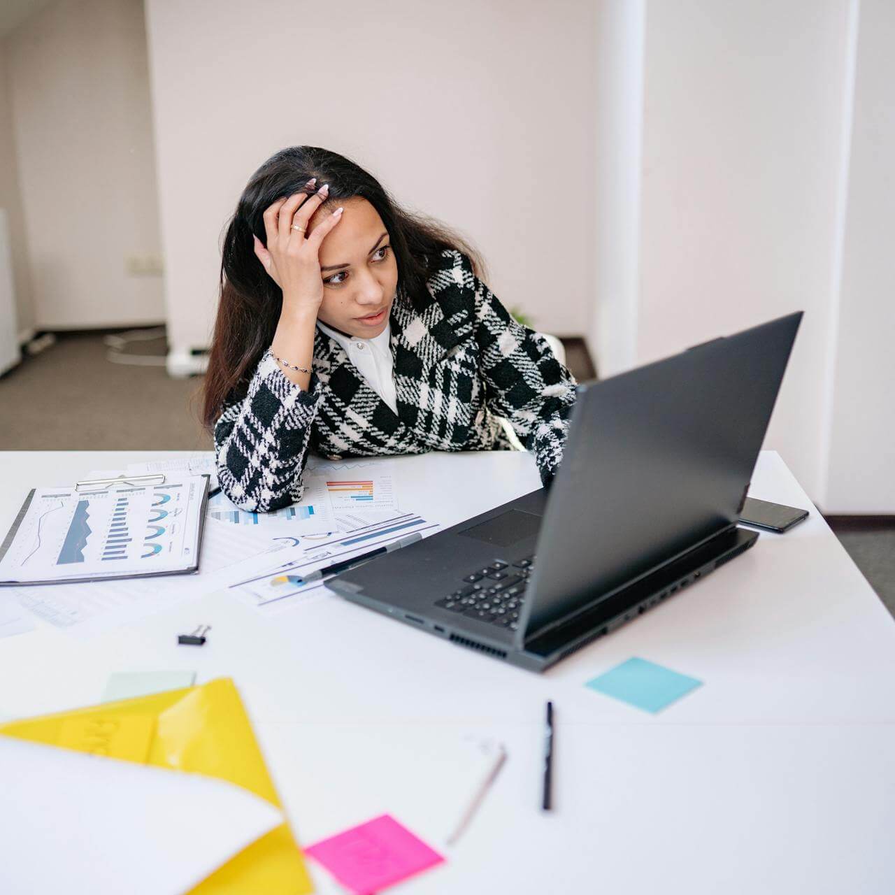 A woman staring at the laptop screen on a white office table